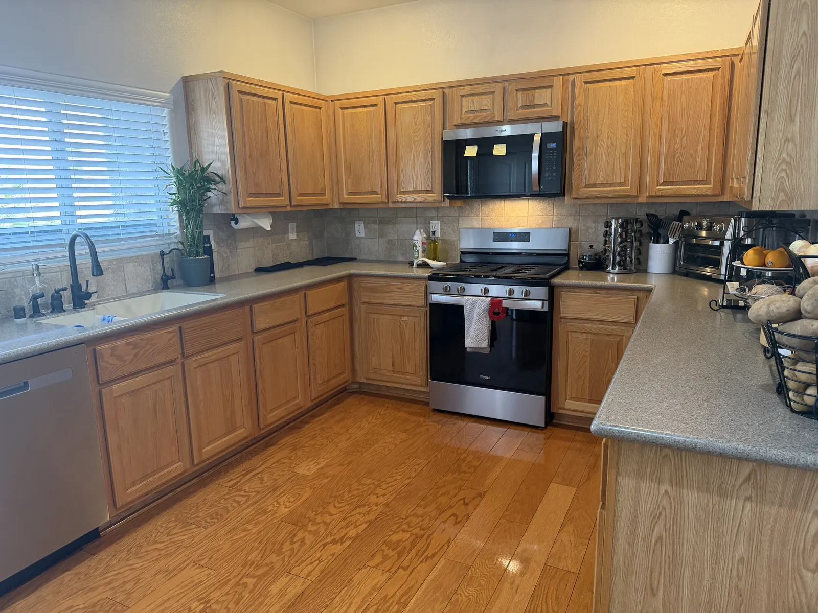 A client’s kitchen after cleaning, with oak cabinets, a clean stainless steel stove and dishwasher, and a polished wood floor